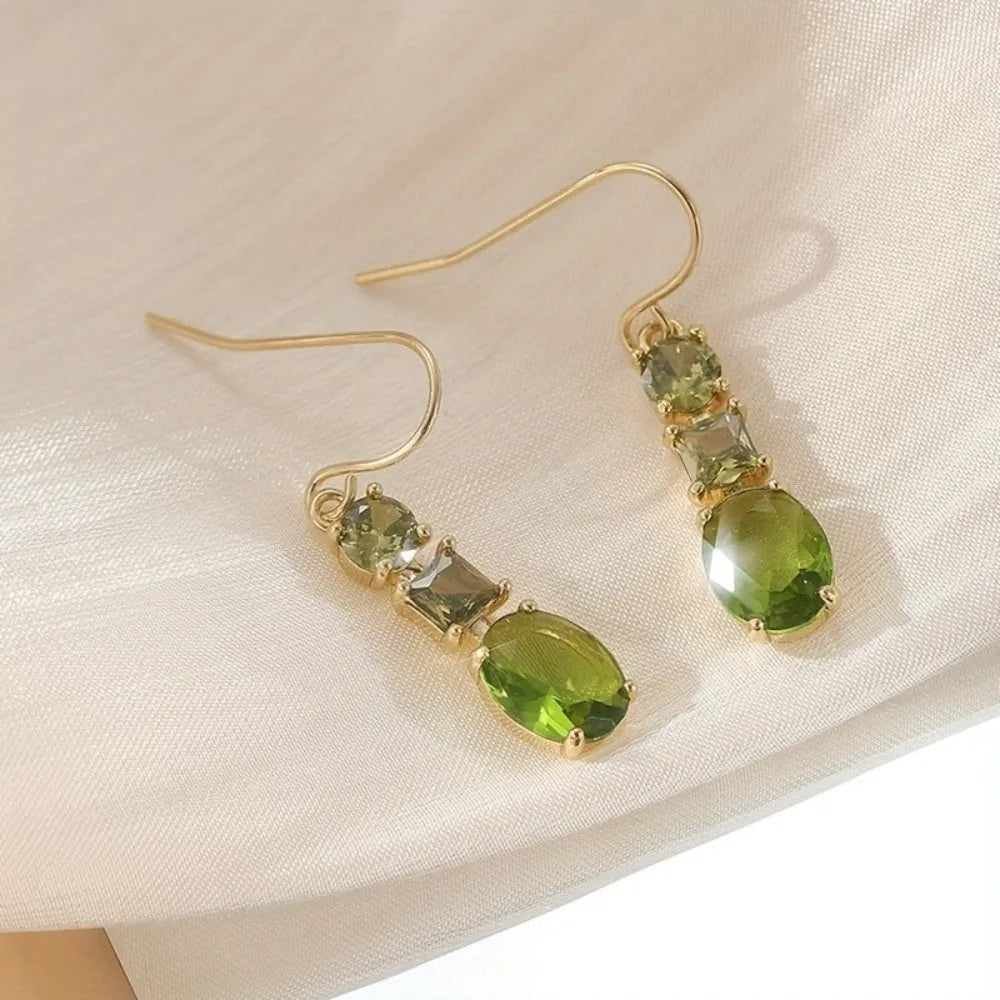 Green geometric copper earrings with a quadrilateral shape on a plain background.
