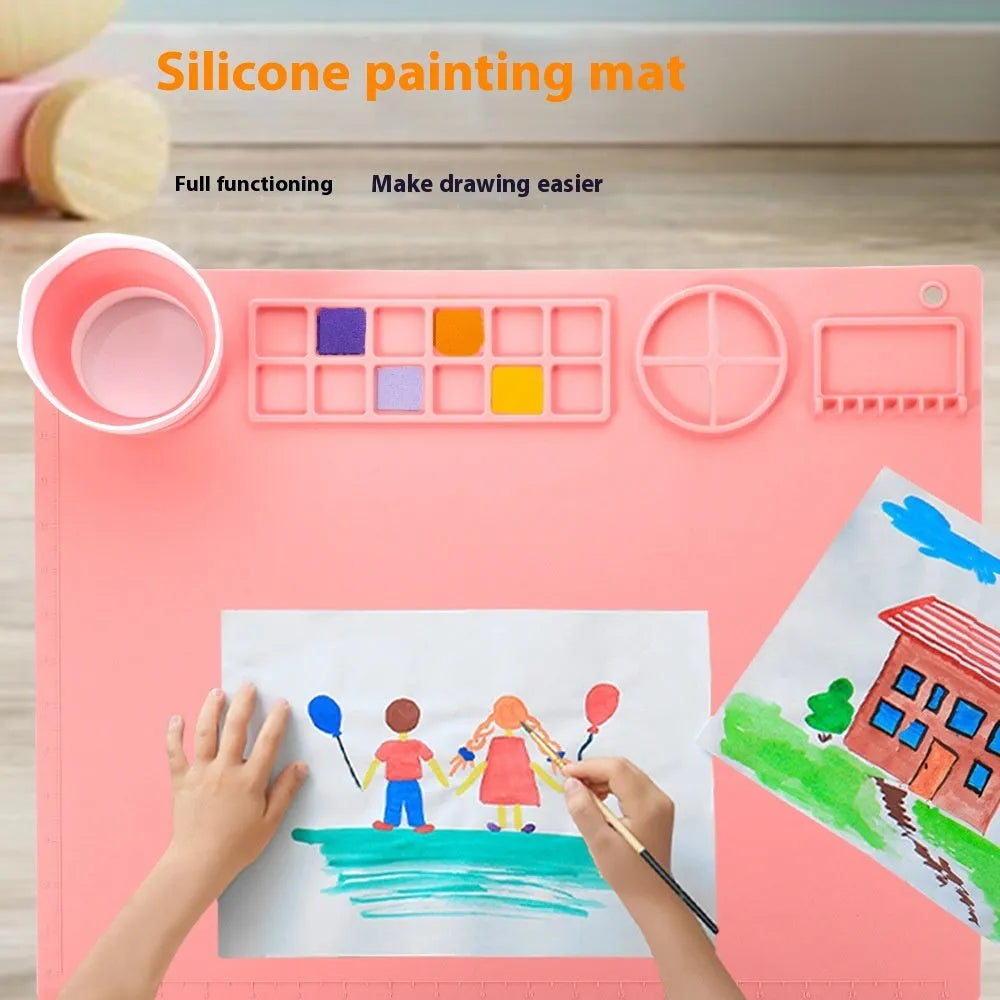Light blue silicone painting mat with two round bowls, placed on a wooden table with paintbrushes.