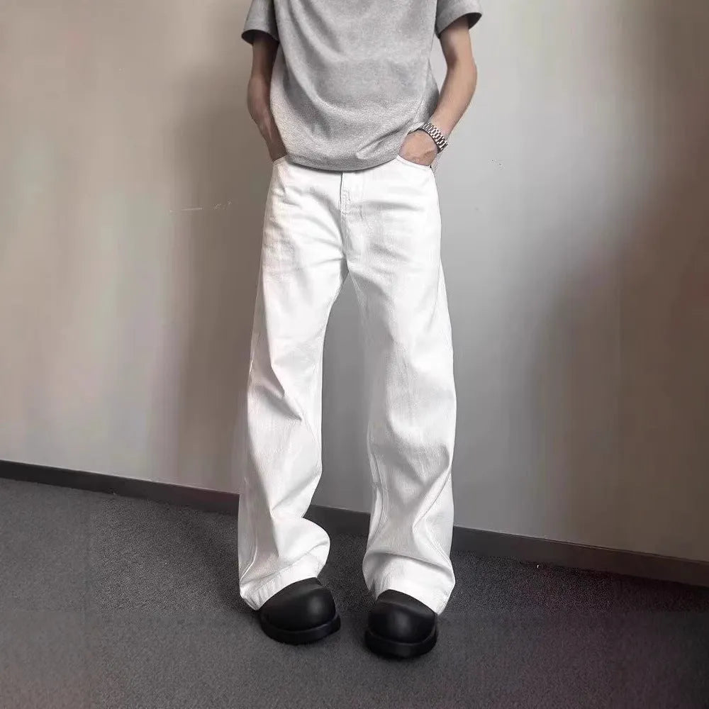 A man wearing white loose straight-leg cotton jeans with a mid-waist and zipper fly.