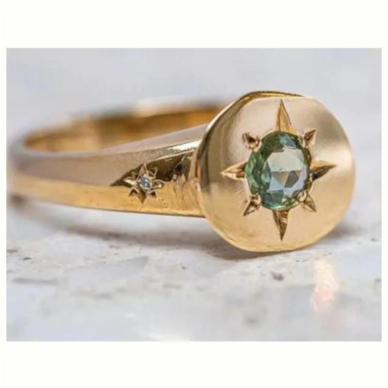 Golden oval ring with a central star-shaped zircon stone on an adjustable band.