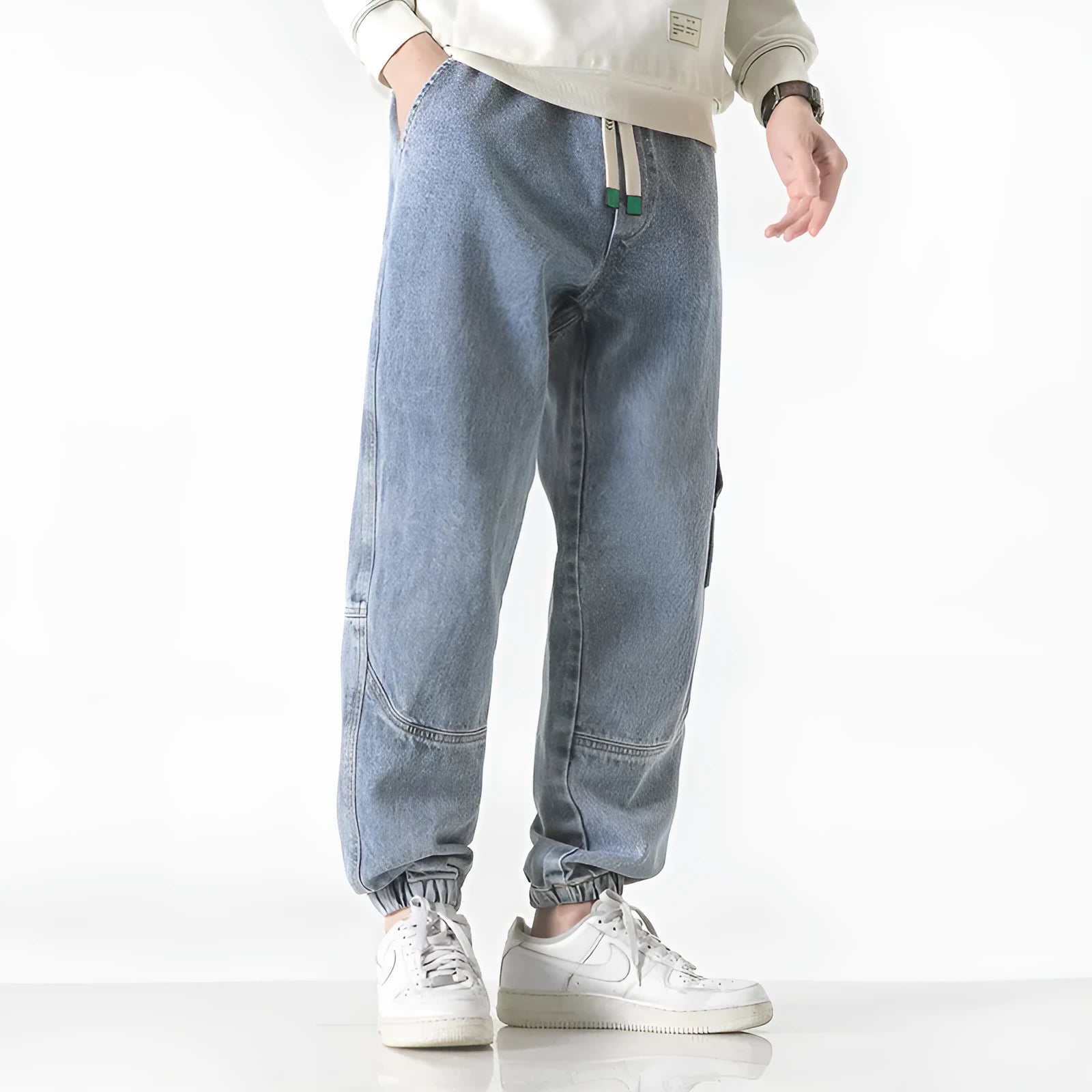Men's loose-fit cotton tapered trousers in grey shown flat.