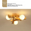 Scandinavian wooden-style ceiling light with three adjustable black lamp heads on angled arms