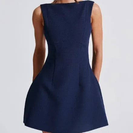 A woman wearing a black backless sling dress with a high waist and short skirt.