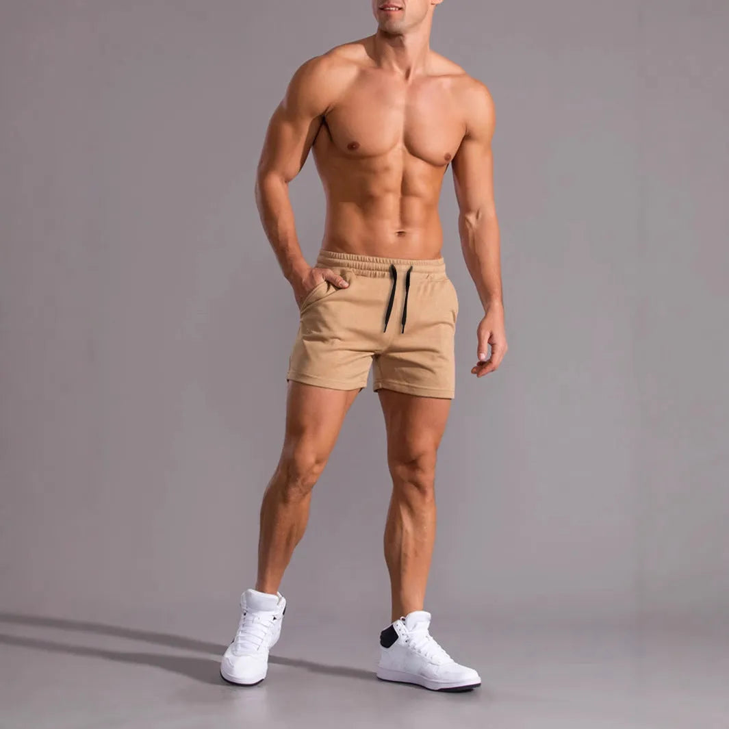 Three pairs of men's solid colour drawstring shorts in black, khaki and light brown laid flat