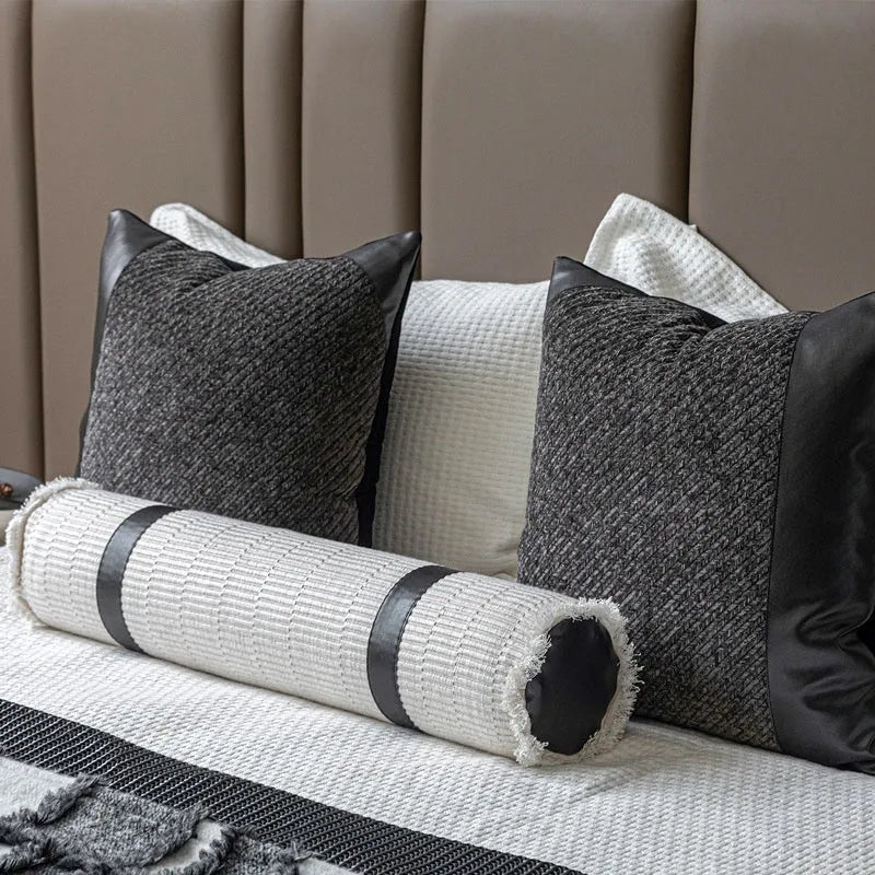 Modern gray and white plaid bed runner blanket with matching pillowcase and round leather-look pillow on a bed.