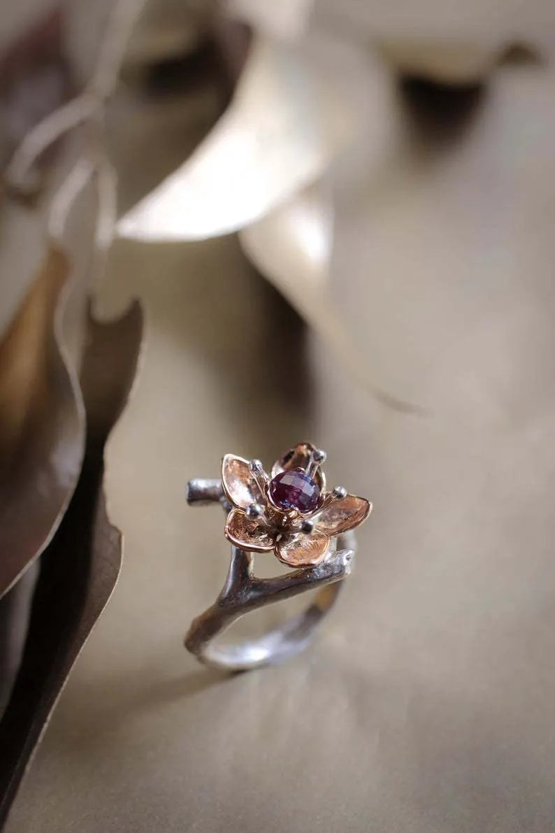 Geometric silver two-tone women's ring with open floral detail on a plain background.