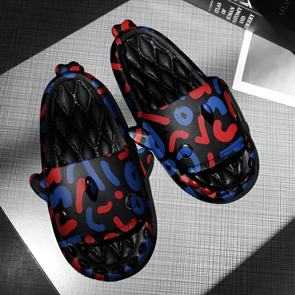 Pair of grey open-toe EVA slippers with raised shark design on the front, shown on a wooden floor.