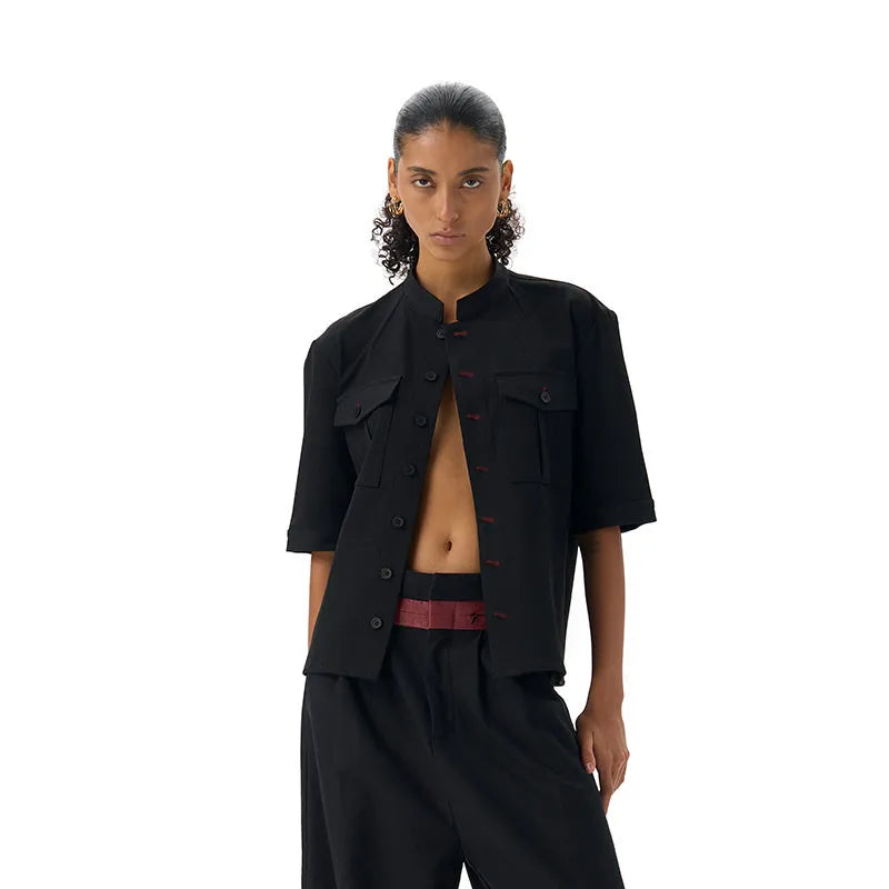 Handmade black half-sleeve hunting shirt with a shirt collar on a hanger.