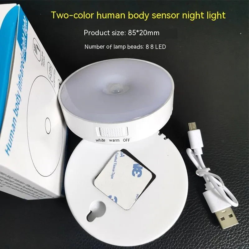Small white circular motion sensing LED night light with USB charging cable and adhesive tape.