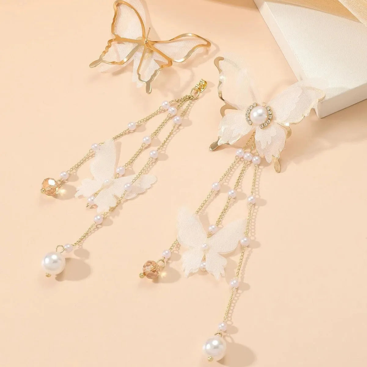 White butterfly tassel drop earrings with faux pearls and clear rhinestones on a copper alloy base.