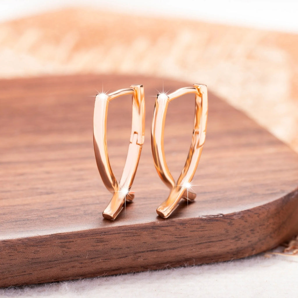 Rose gold plated cross earrings on a white background, showing post and clutch fitting.