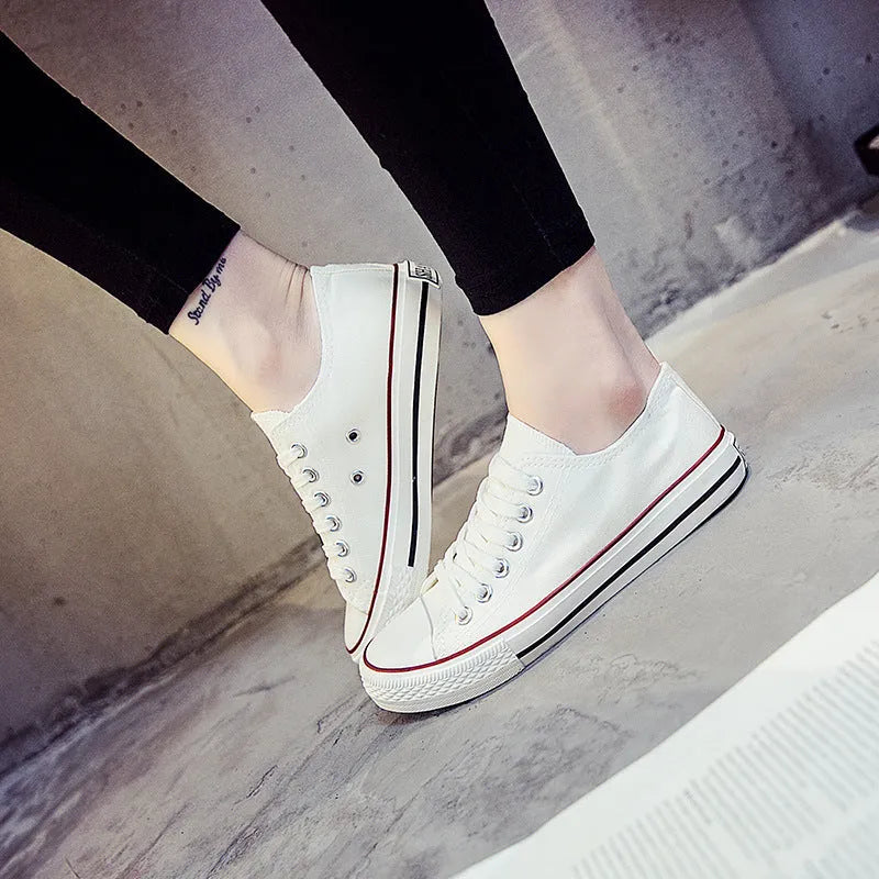 A pair of solid colour canvas lace-up trainers for women on a summer background.