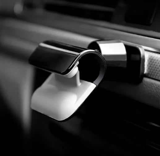 Black car phone holder with 360-degree rotation mounted on vehicle dashboard holding smartphone