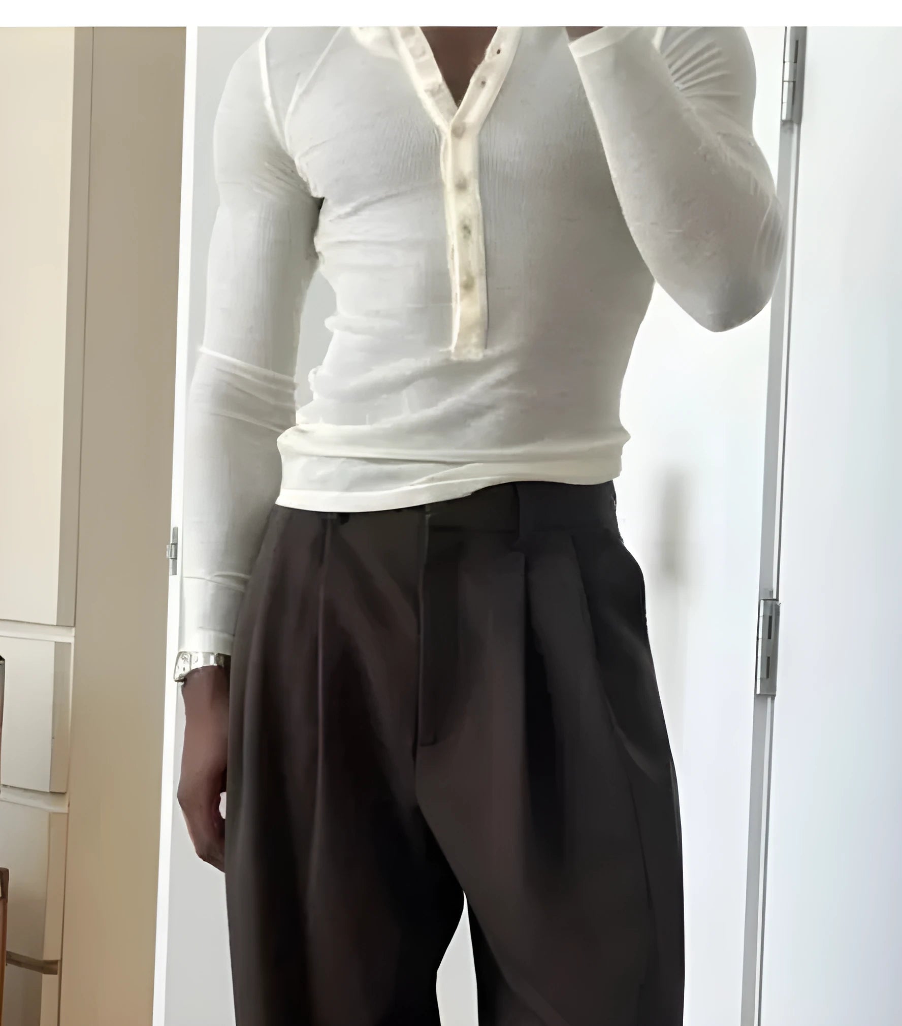 A cream-coloured men's ribbed long-sleeve henley top with a buttoned placket on a hanger.