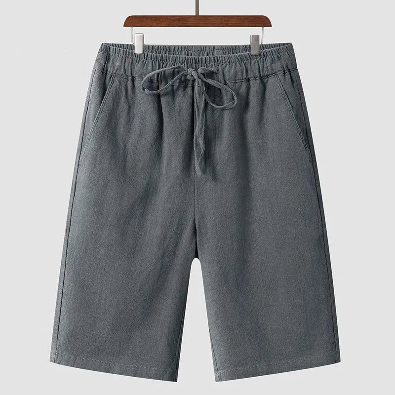 Man wearing beige linen loose-fit cropped shorts on a summer day.