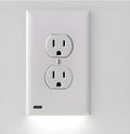 White plug-in socket induction night light installed in a UK wall socket, showing a soft glow from the integrated LEDs.