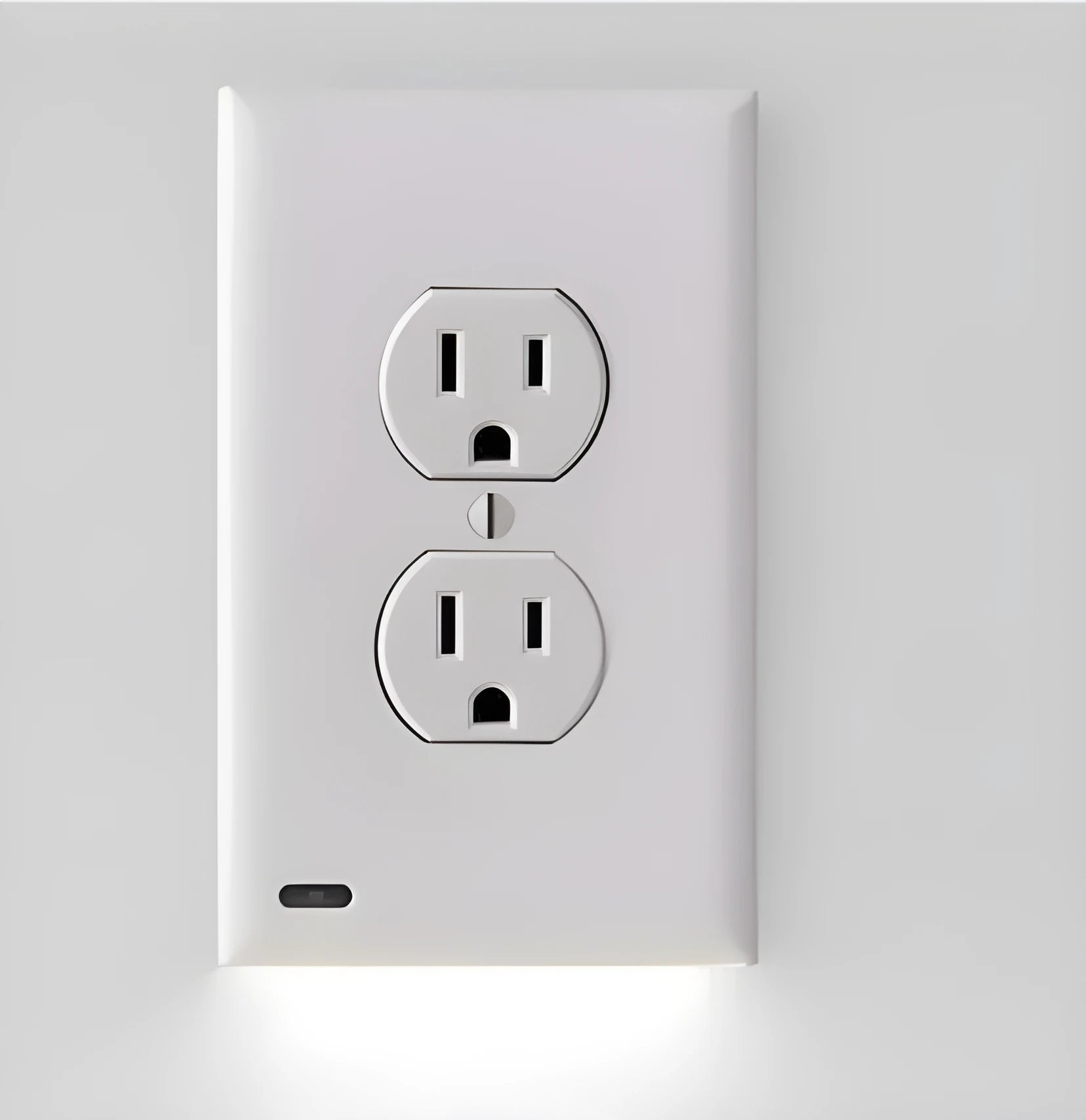 White plug-in socket induction night light installed in a UK wall socket, showing a soft glow from the integrated LEDs.