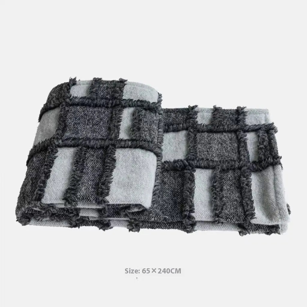 Modern minimalist grey and white plaid polyester bed runner with dark grey pillowcase and round leather pillow on bed