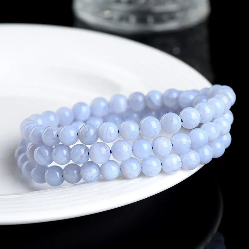 Close-up of a handmade blue agate bracelet with natural striped beads on a wrist.