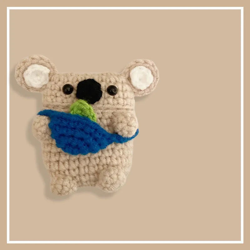 Hand-knitted grey koala bear backpack design earphone cover for Apple AirPods on a table.
