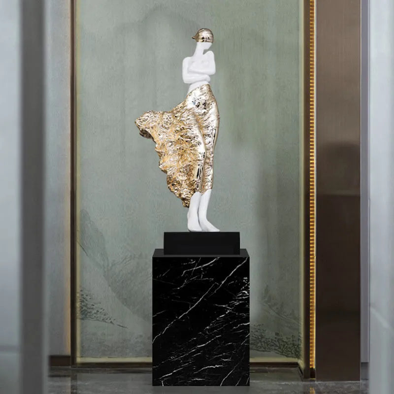 Tall modern sculptured character ornament in a metallic rose gold finish on a table.
