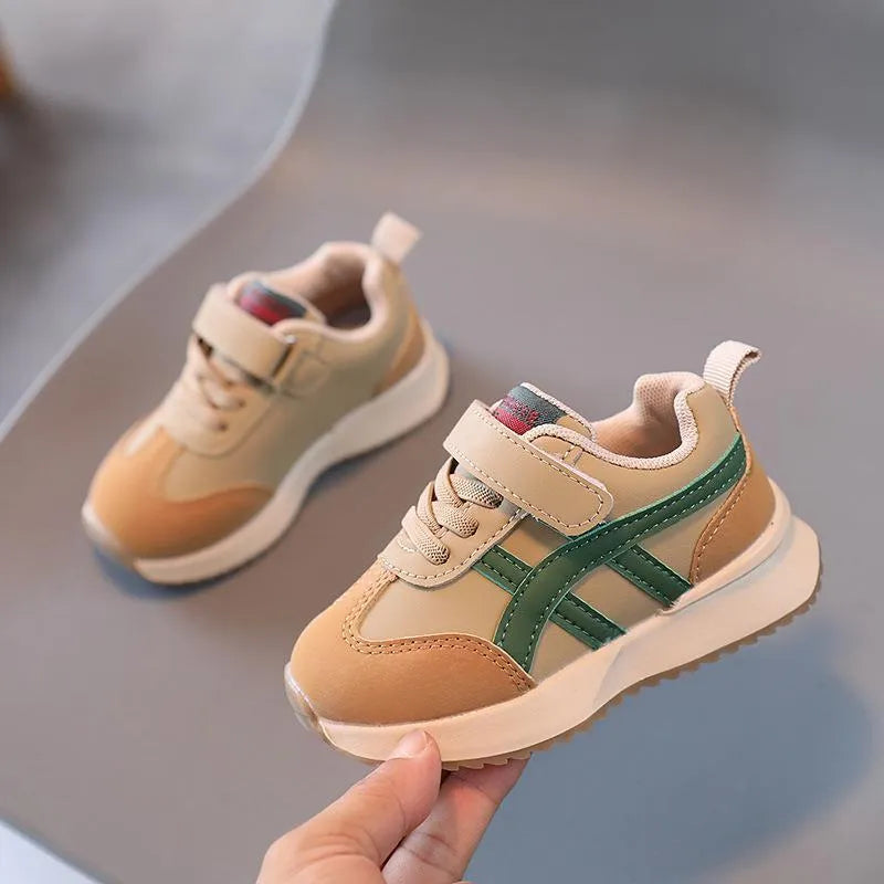 White children's sneakers with Velcro strap and textured rubber sole on a neutral background