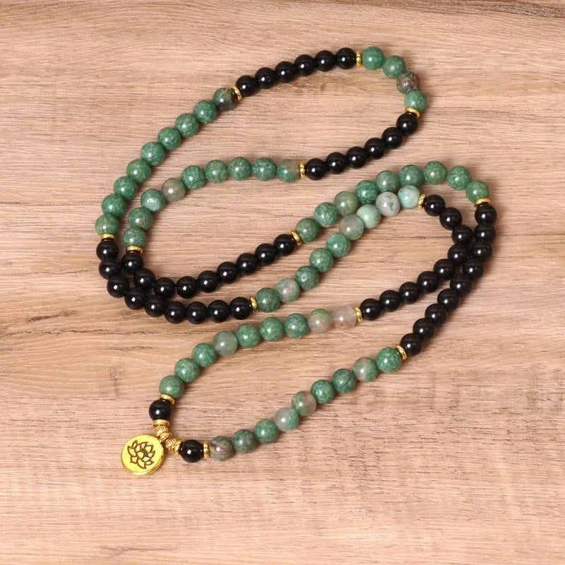 Green and black alloy beads on an elasticated bracelet, shown on a wrist.
