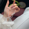 White bow pearl necklace with geometric clasp on woman at clavicle length