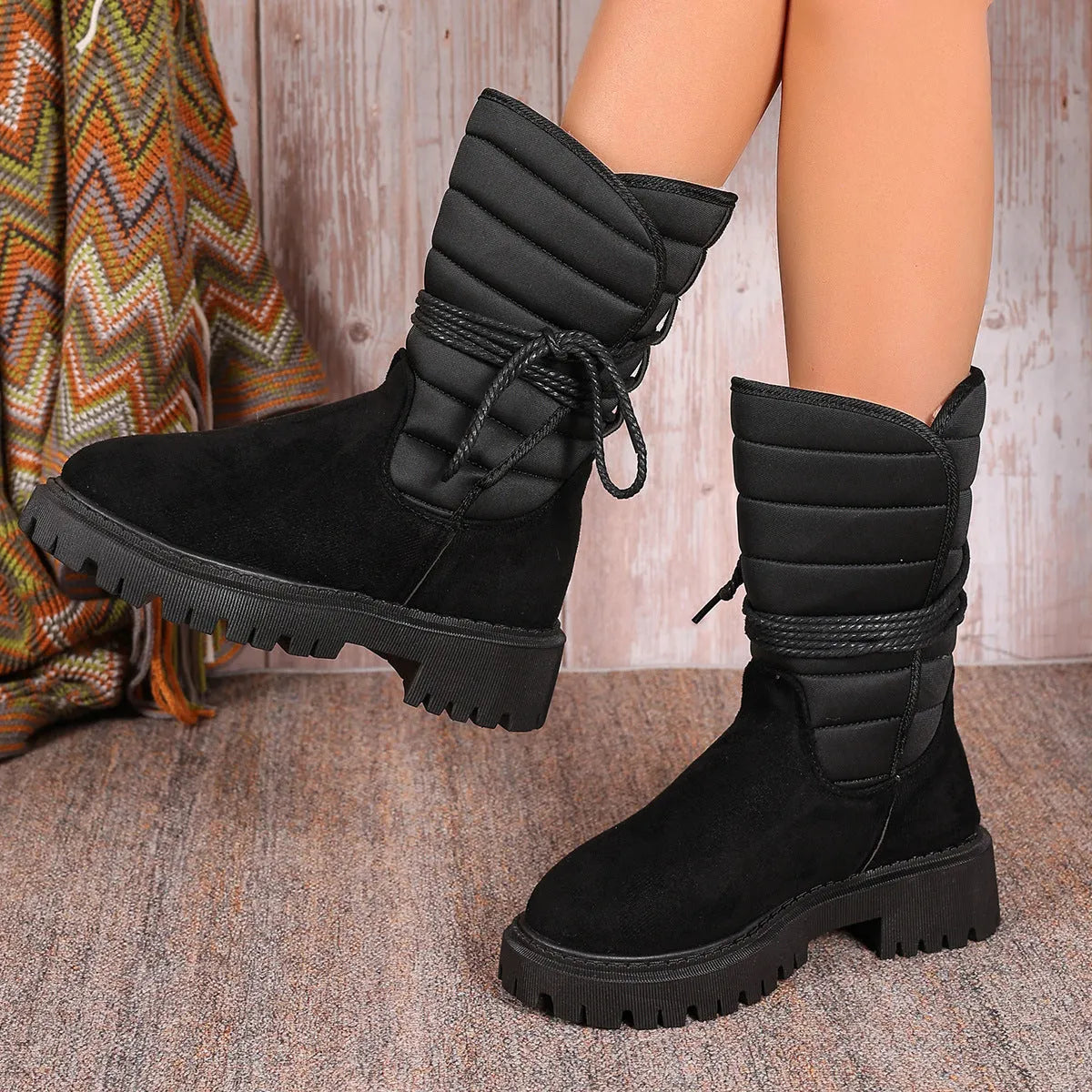 Women's black chunky heel snow boots with lace-up design and suede upper.