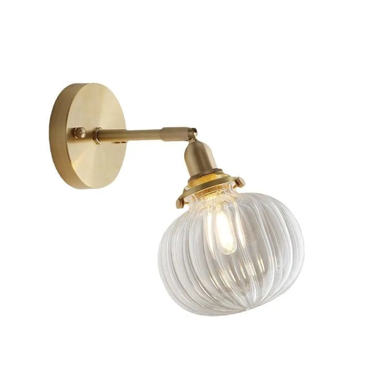 Close-up of a hand-blown pumpkin-shaped glass wall lamp in blue, mounted on a beige wall.
