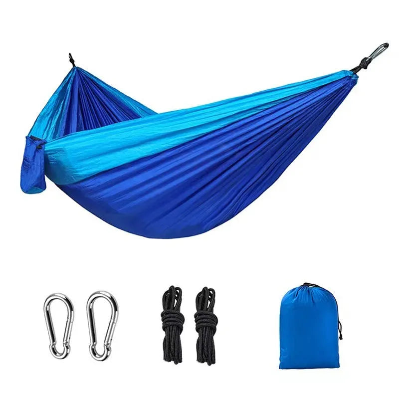 Blue nylon parachute camping hammock hung between two trees, showing its full 270cm length and 140cm width.