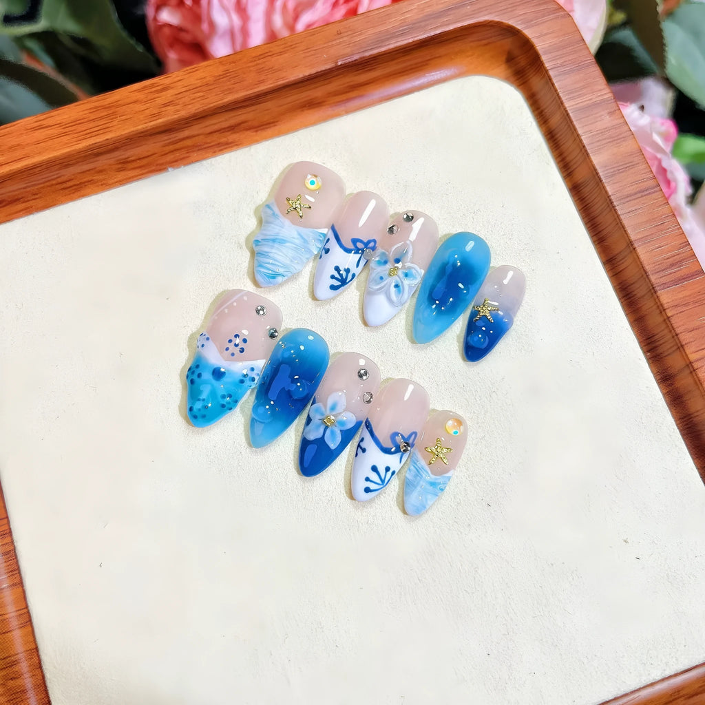 Blue hand-painted carved plastic fake nails on a clear background.