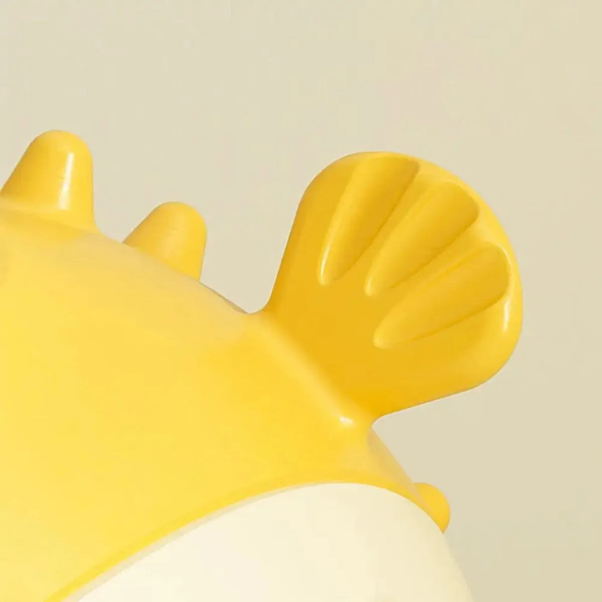 Yellow vinyl fish-shaped dog chew toy with textured surface and squeaker inside.