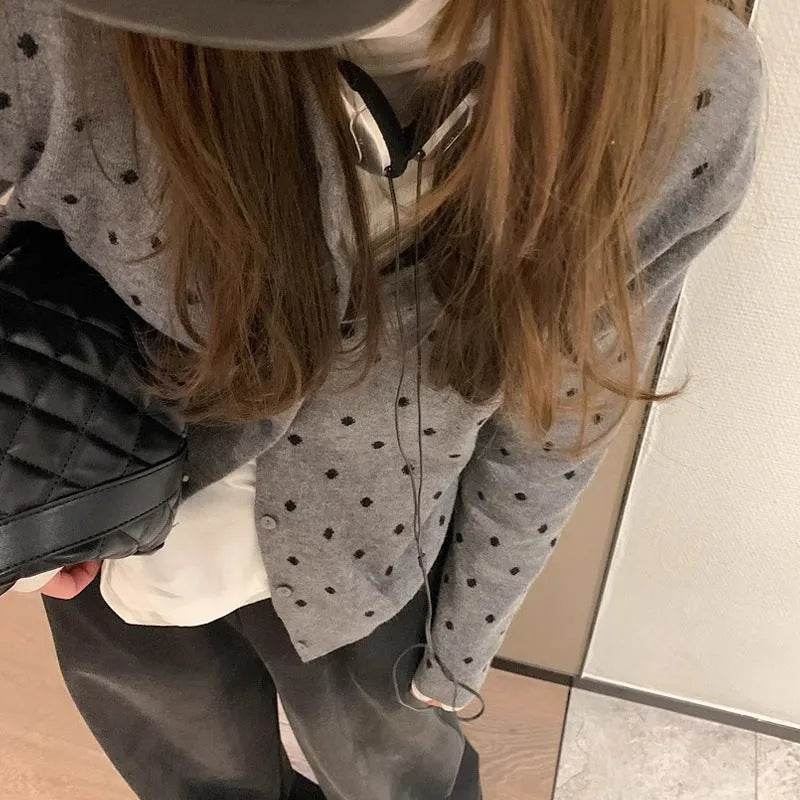 Women's grey dot knitted cardigan with crocheted flower detail on front, shown in loose fit.