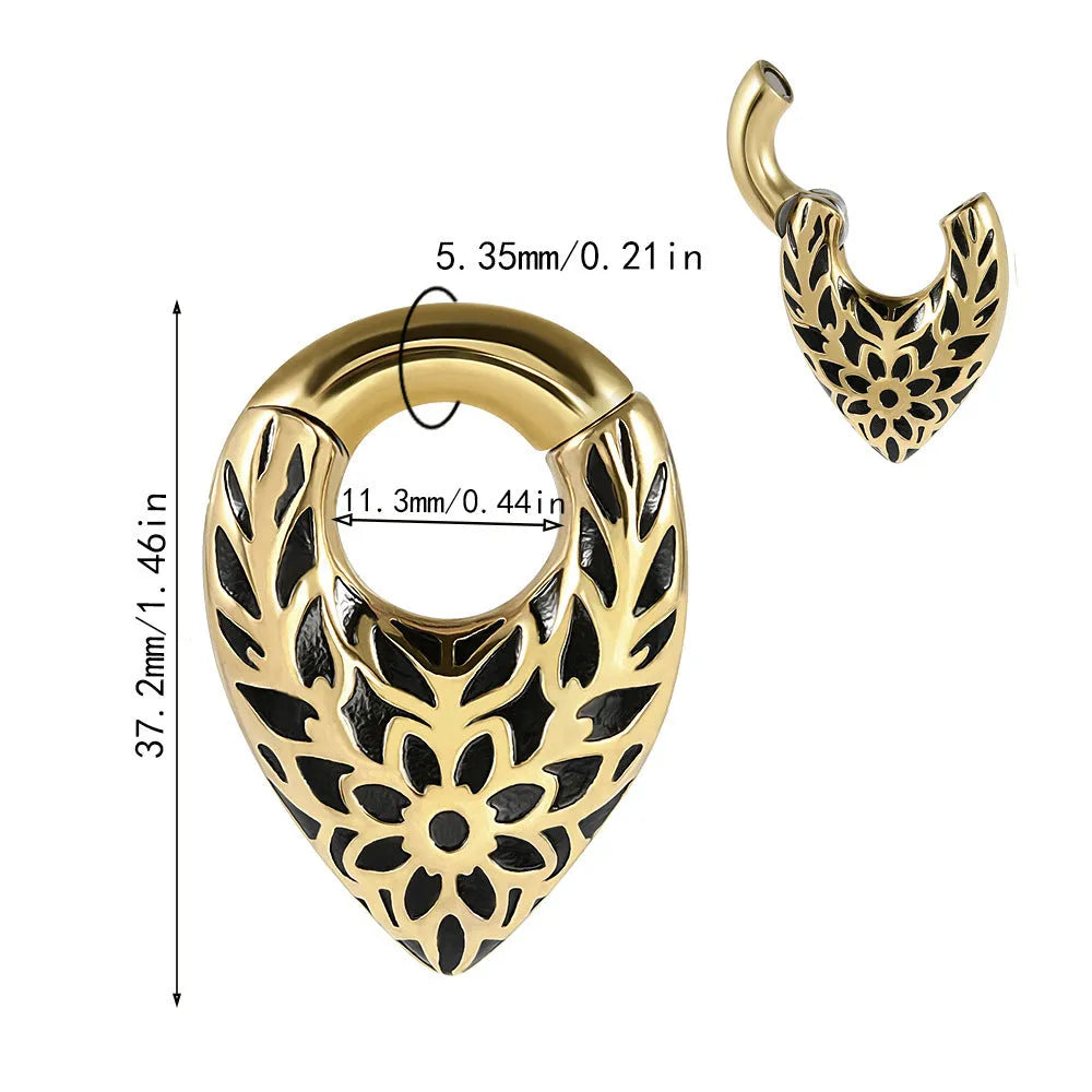 Close-up of a stainless steel drop-shaped ear extender with totem patterns, hanging vertically.