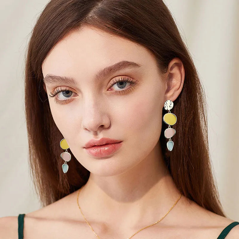 Sterling silver alloy Morandi three-colour oil drip simple wafer disc earrings on a white background.