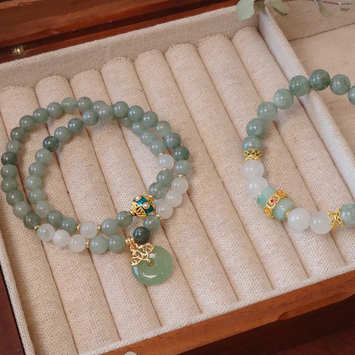 Close-up of a women's Myanmar jade bracelet with a geometric safety buckle pendant and lucky beads.