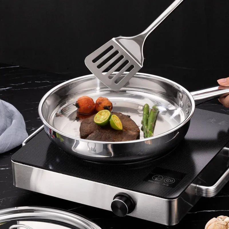 15-piece stainless steel non-stick cookware set with glass lids, spoons, and shovel on a table