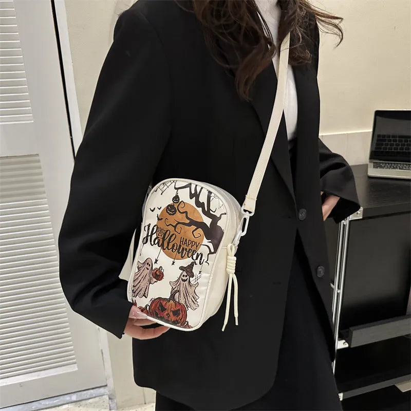 Black Halloween crossbody bag with orange pumpkin, white ghost, and black bat print, showing front zip and adjustable strap.