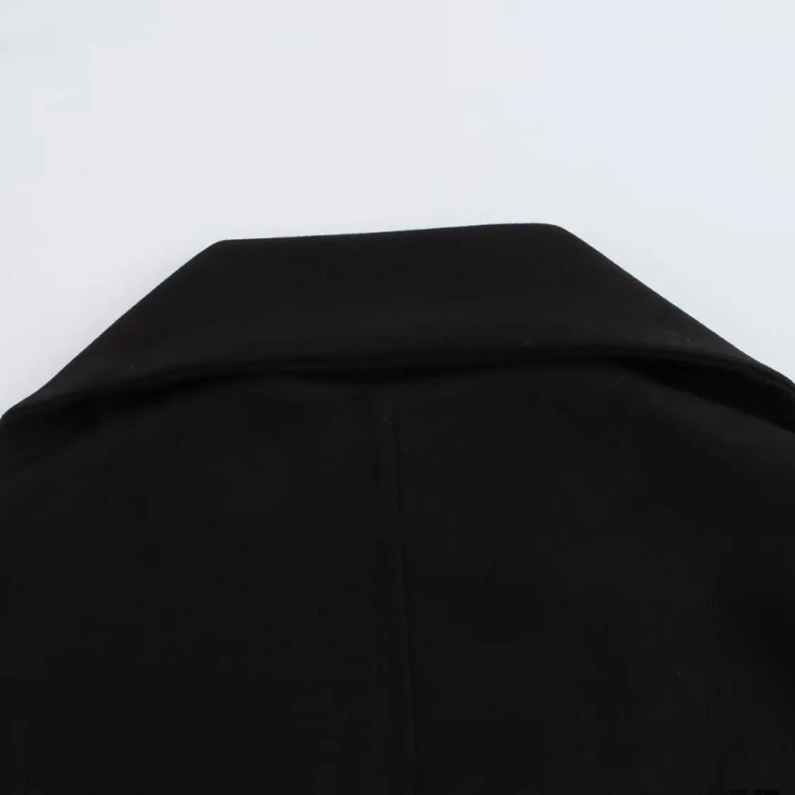 Women's long black polyester overcoat with a fluffy artificial fur collar, shown on a hanger.