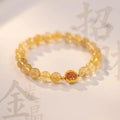 Citrine gold rutilated quartz crystal bracelet with diamond-cut beads on a wrist.