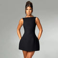 A woman wearing a black backless sling dress with a high waist and short skirt.
