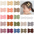 Assortment of pastel-coloured barrette and bow hair clips for babies and toddlers on a white background.
