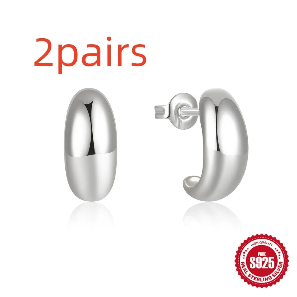 Close-up of a glossy C-shaped sterling silver stud earring in a gold electroplated finish.