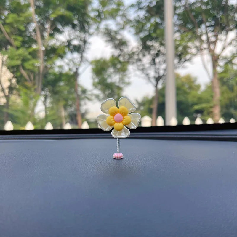 Small colourful plastic swing ornament for car dashboard, shown in blue, green, pink, purple, and yellow.