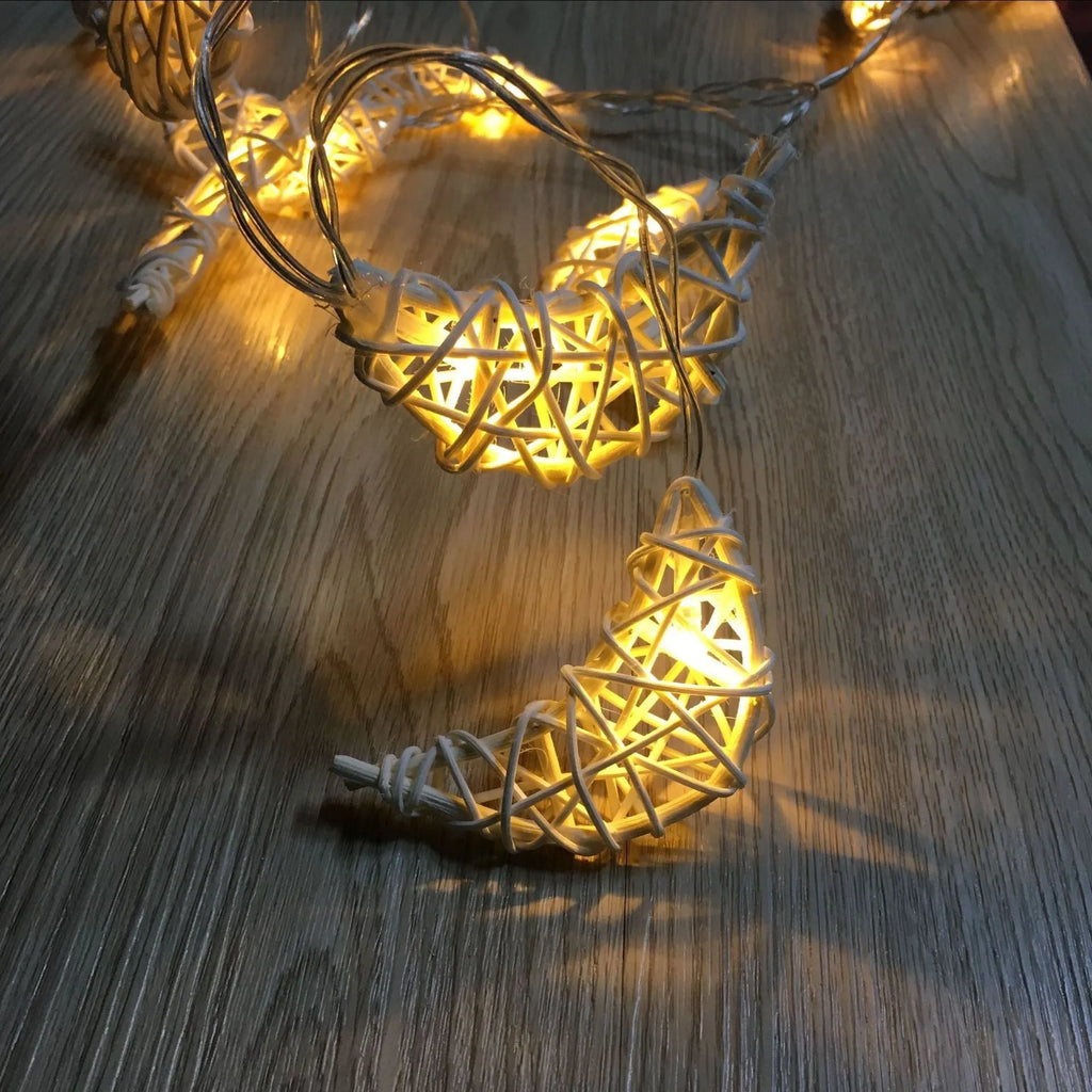 Handwoven rattan moon pendant fairy light chain with warm white glow on a dark background