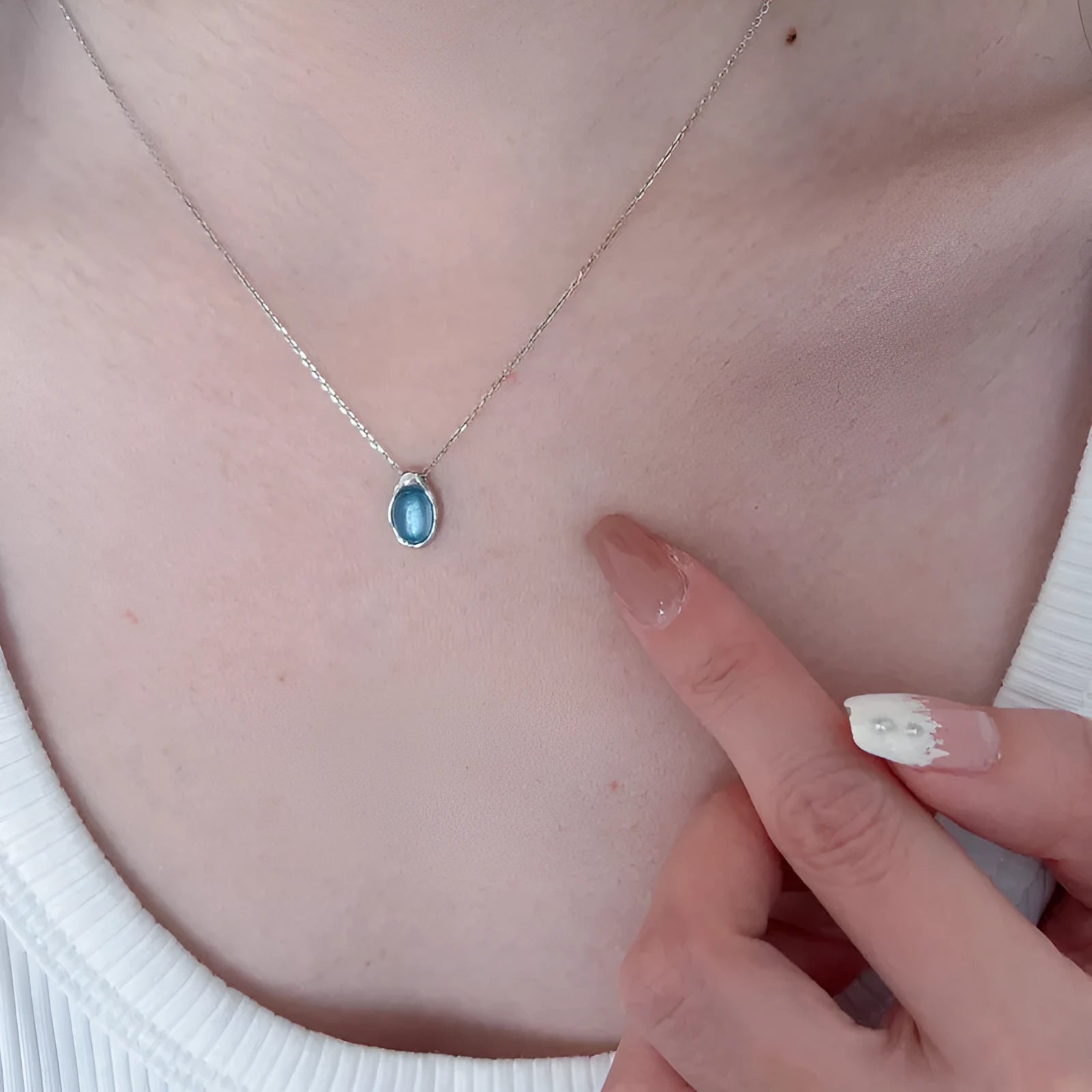 Navy blue water drop pendant necklace on a model, showing the adjustable cross chain and geometric copper design.