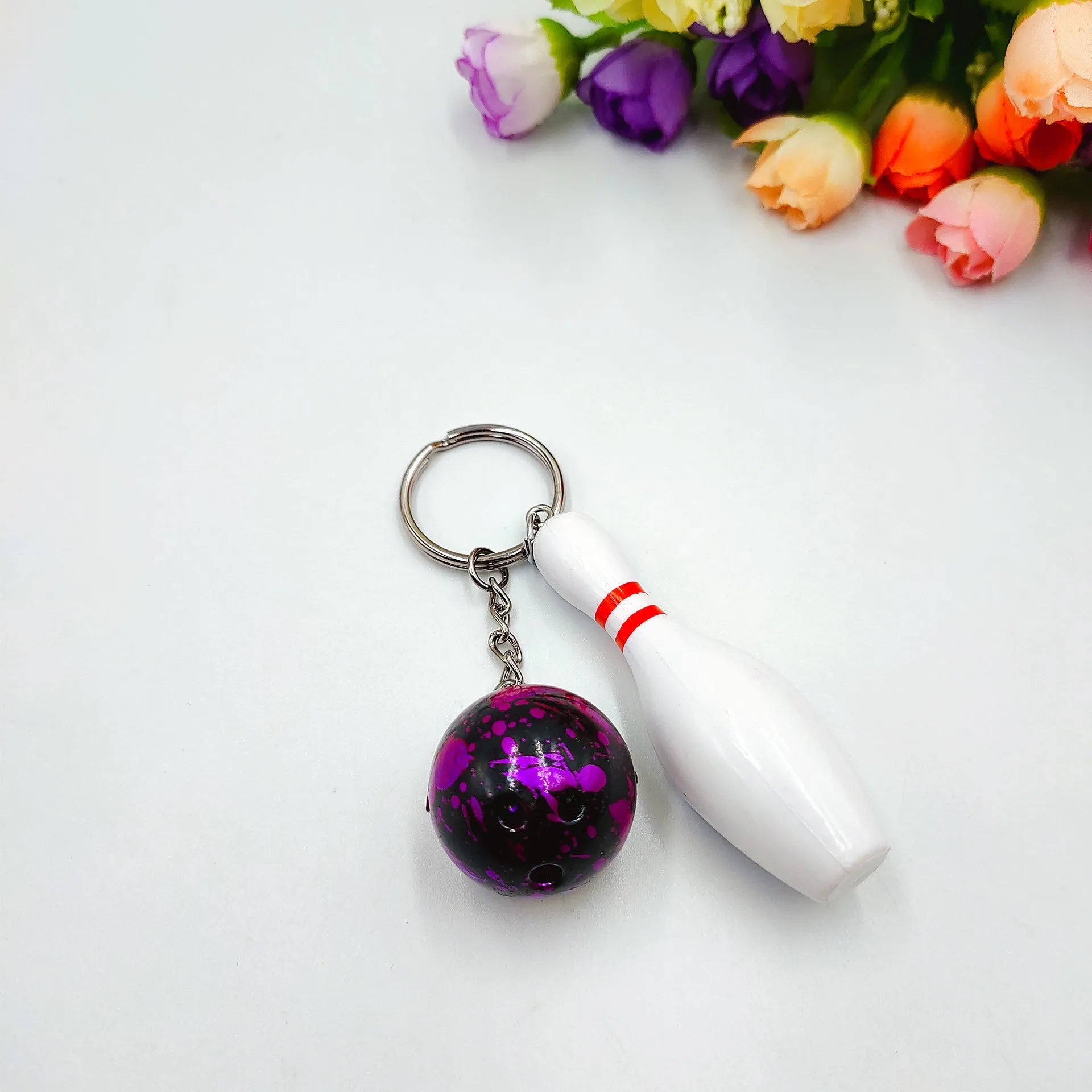 Mini bowling ball keychain pendant in PVC metal showing four colour options: dark red, blue, purple, green