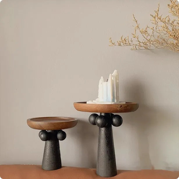 Nordic style round wooden tray with high legs for displaying candles and aromatherapy items.