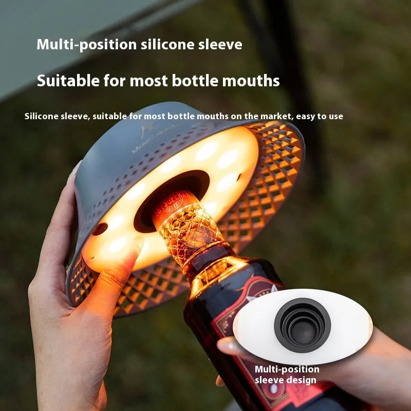 Beige plastic camping lantern shaped like a wine bottle with a glowing LED light inside on a wooden surface.